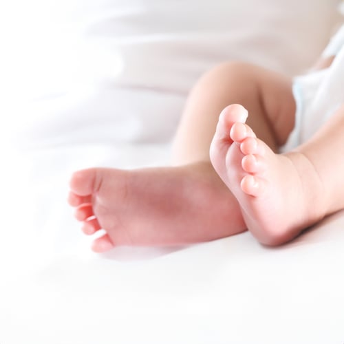 Close-up of a newborn baby’s feet resting on a soft white surface, symbolising innocence, warmth, and the beginning of life.